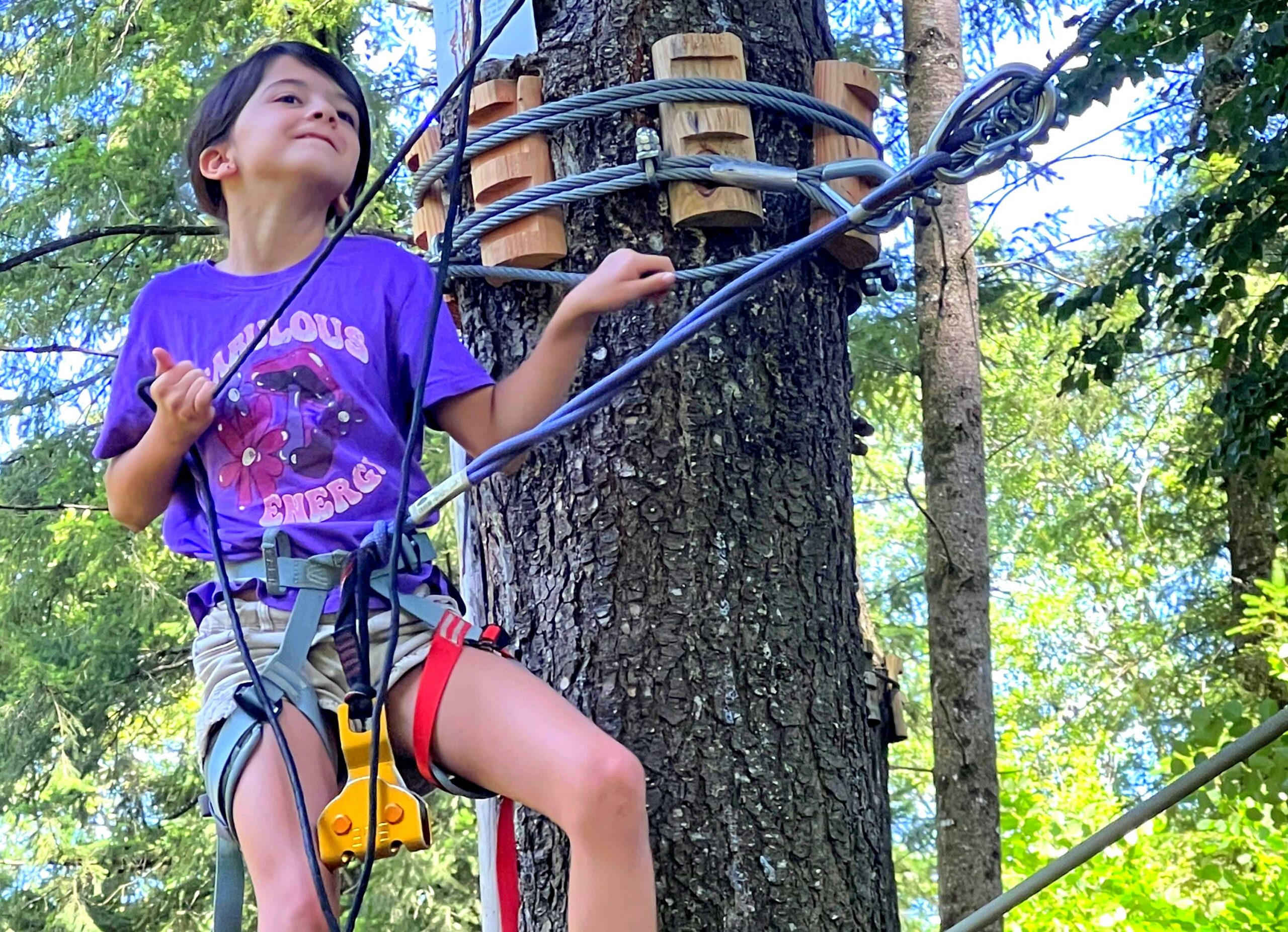 Jeune fille sur l’accrobranche du camping Les Trois Sources, équipée avec ligne de vie continue et matériel de sécurité Zaza, activité nature et familiale.