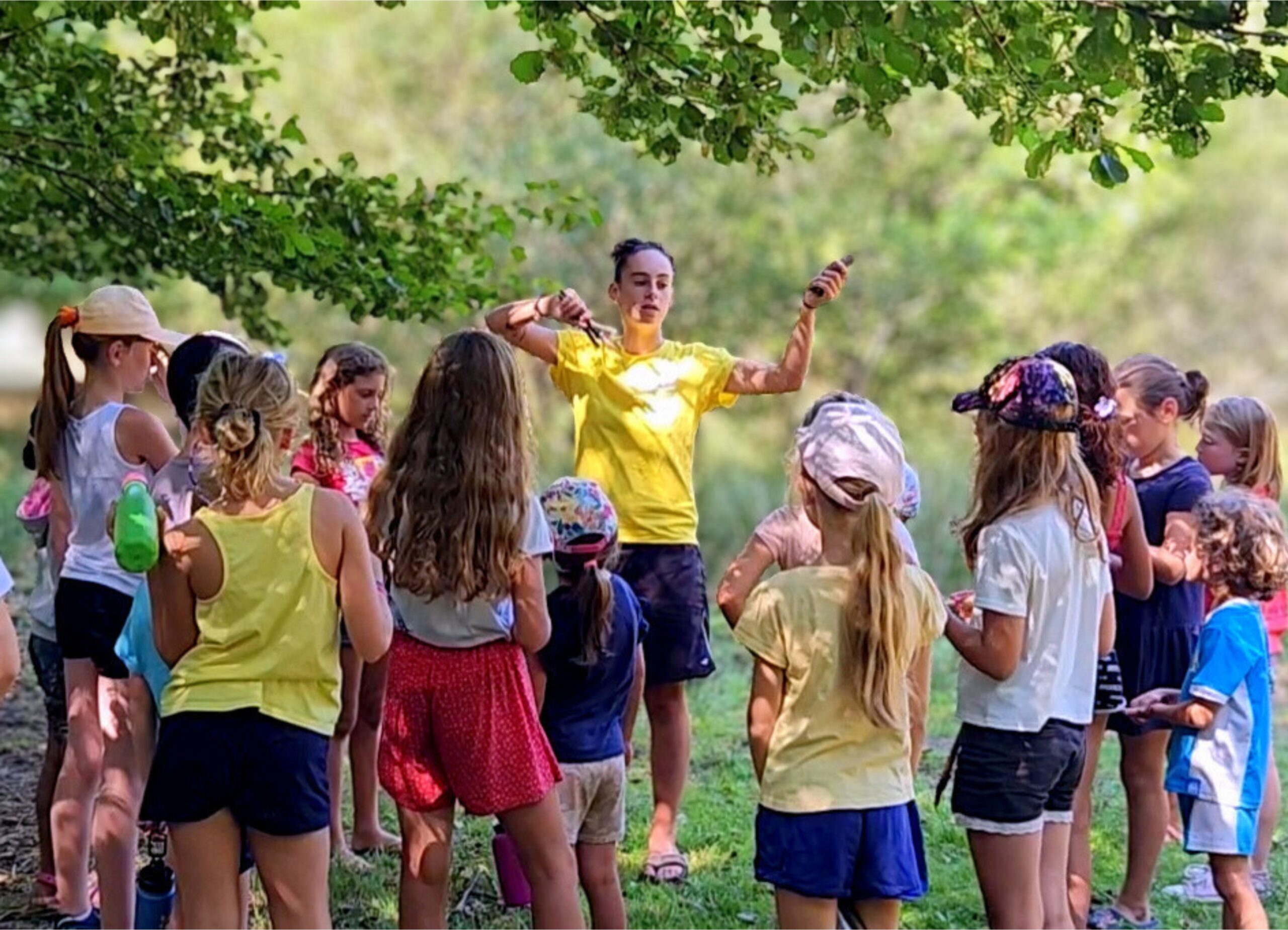 1 Enfants au Club Enfant du camping Les Trois Sources écoutant l’animatrice au bord de l’étang, activité familiale et éducative en plein air.