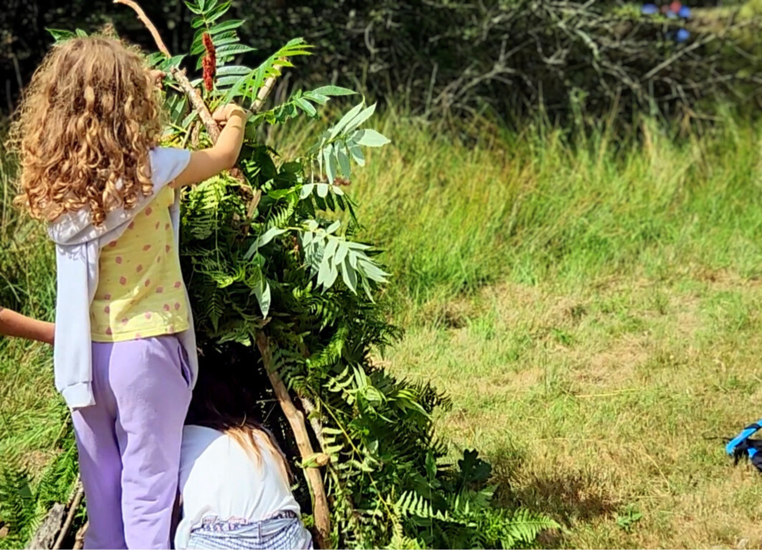 club enfant Enfant construisant une cabane avec des branches et des feuillages au Club Enfant du camping Les Trois Sources dans le Lot, région Occitanie, activité créative et nature.