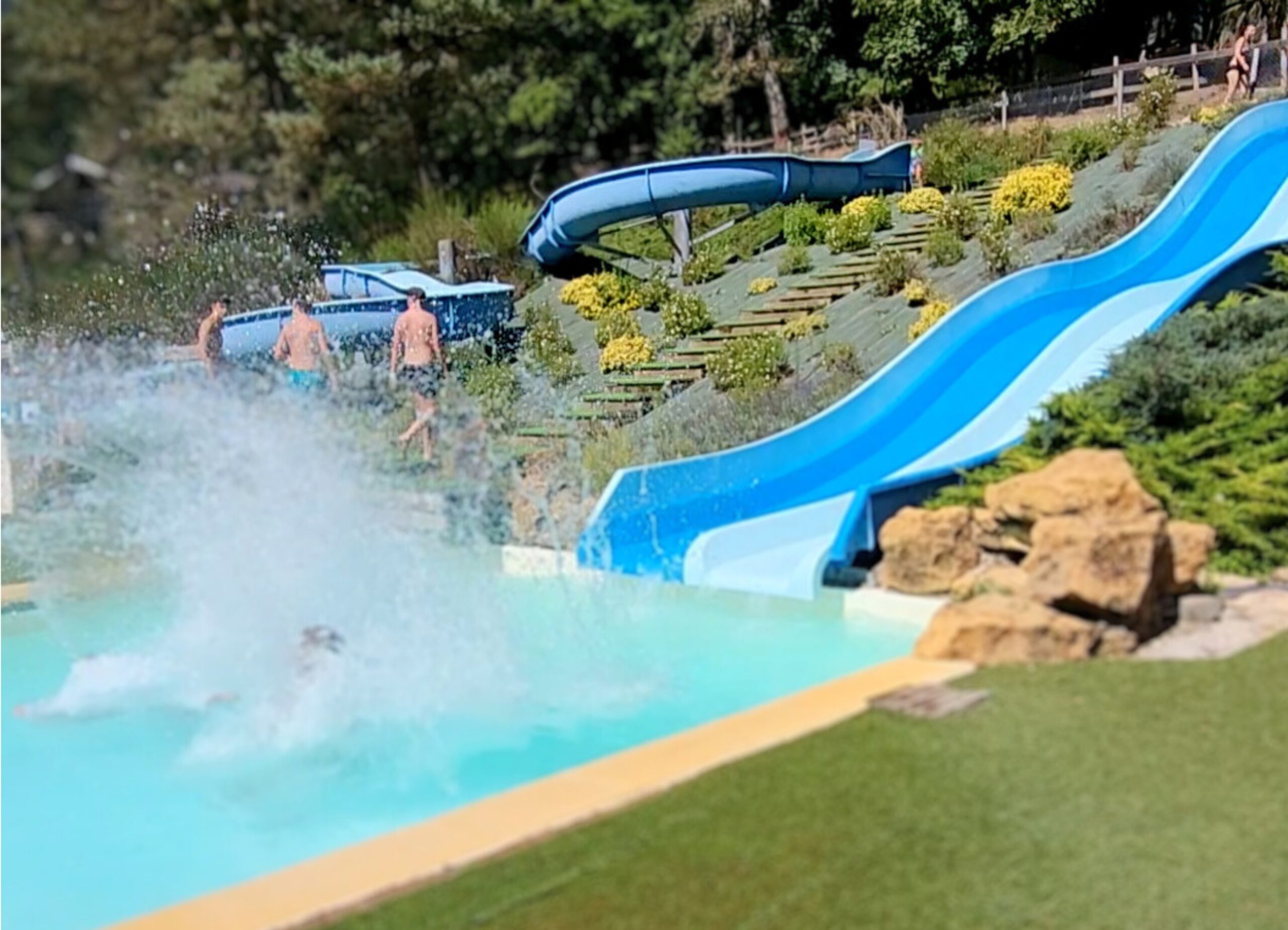 piscine Toboggan des piscines du camping Les Trois Sources avec un enfant arrivant dans l’eau dans le Lot, région Occitanie, activité ludique et familiale.