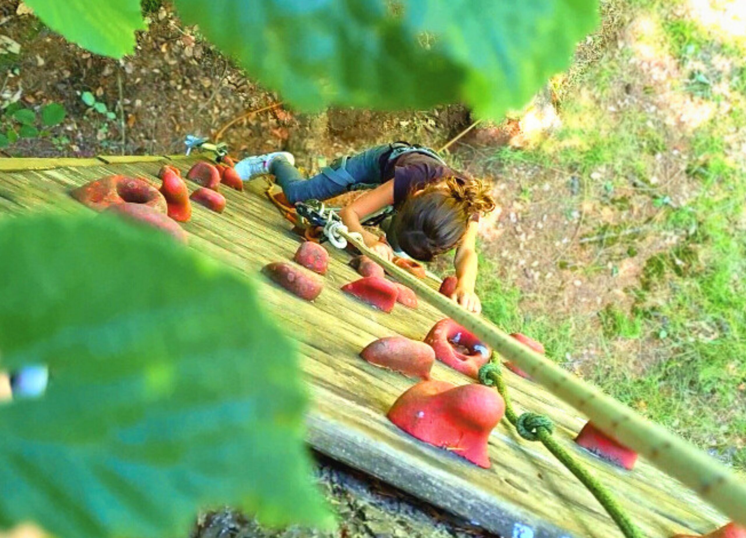 accrobranche Jeune fille escaladant le mur du deuxième parcours d’accrobranche du camping Les Trois Sources dans le Lot, région Occitanie, activité sportive et familiale en plein air.
