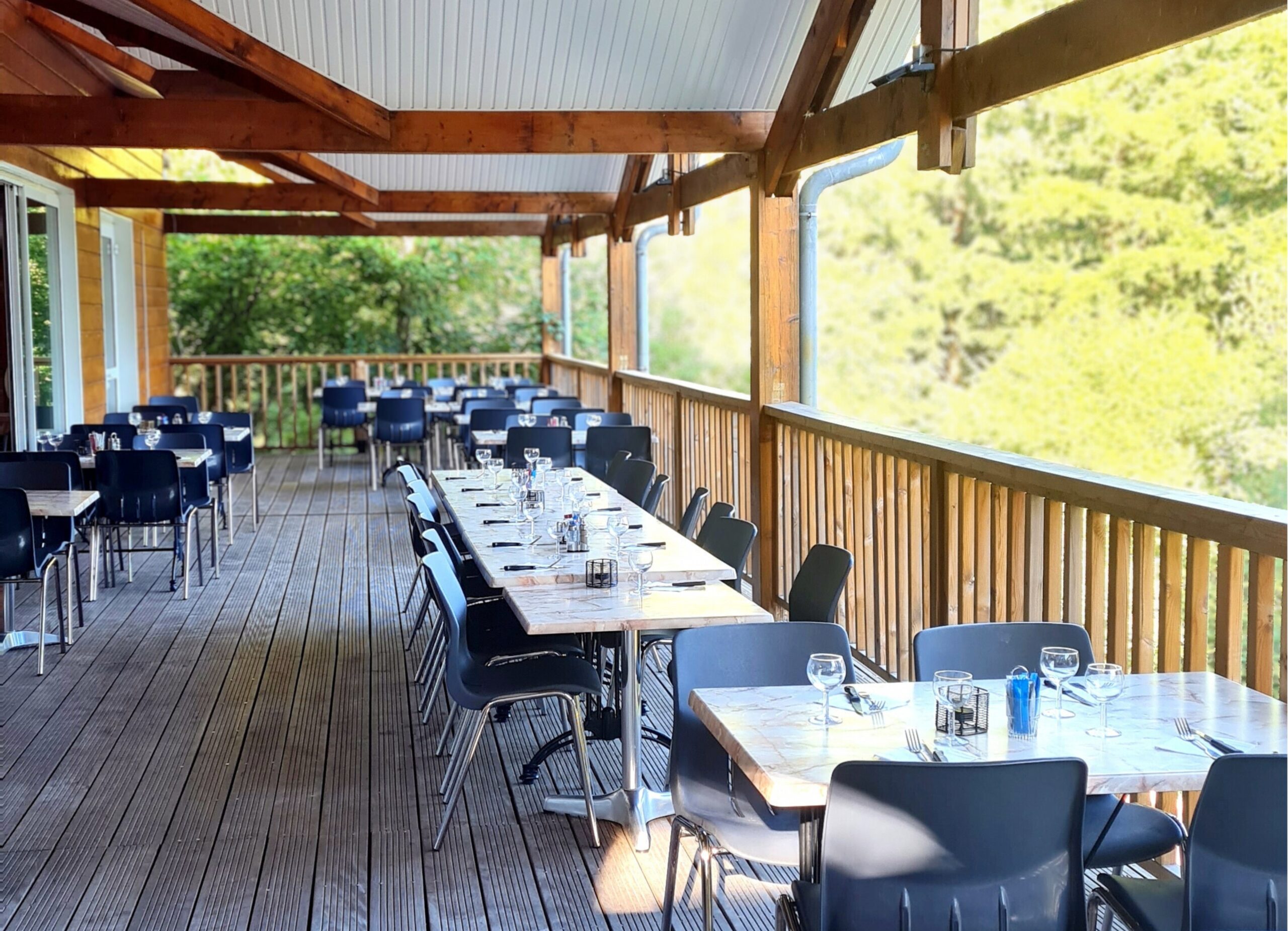 Terrasse suspendue du restaurant du camping Les Trois Sources dans le Lot, région Occitanie, espace convivial et panoramique en pleine nature.