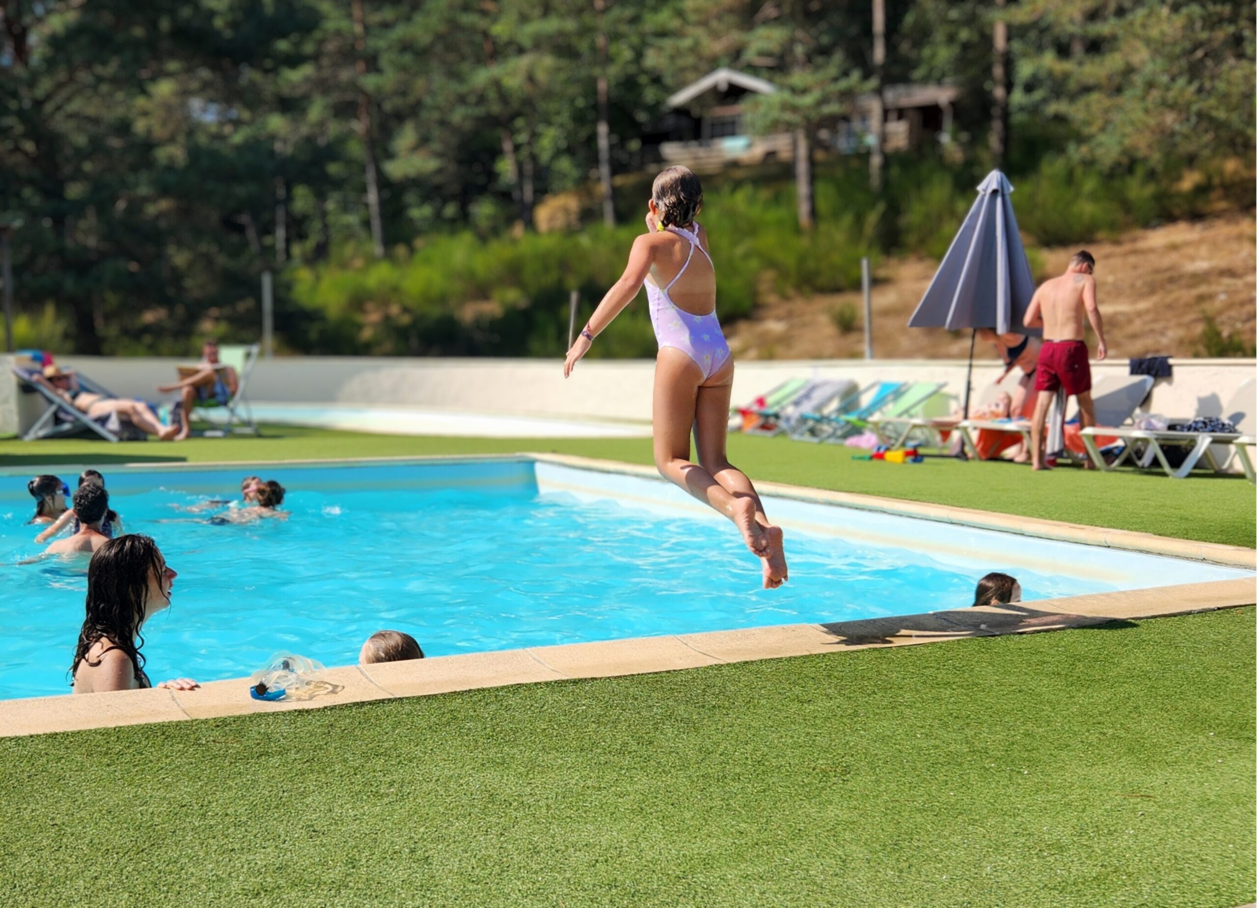 piscine Petite fille sautant dans la piscine du camping Les Trois Sources dans le Lot, région Occitanie, activité ludique et familiale en plein air.