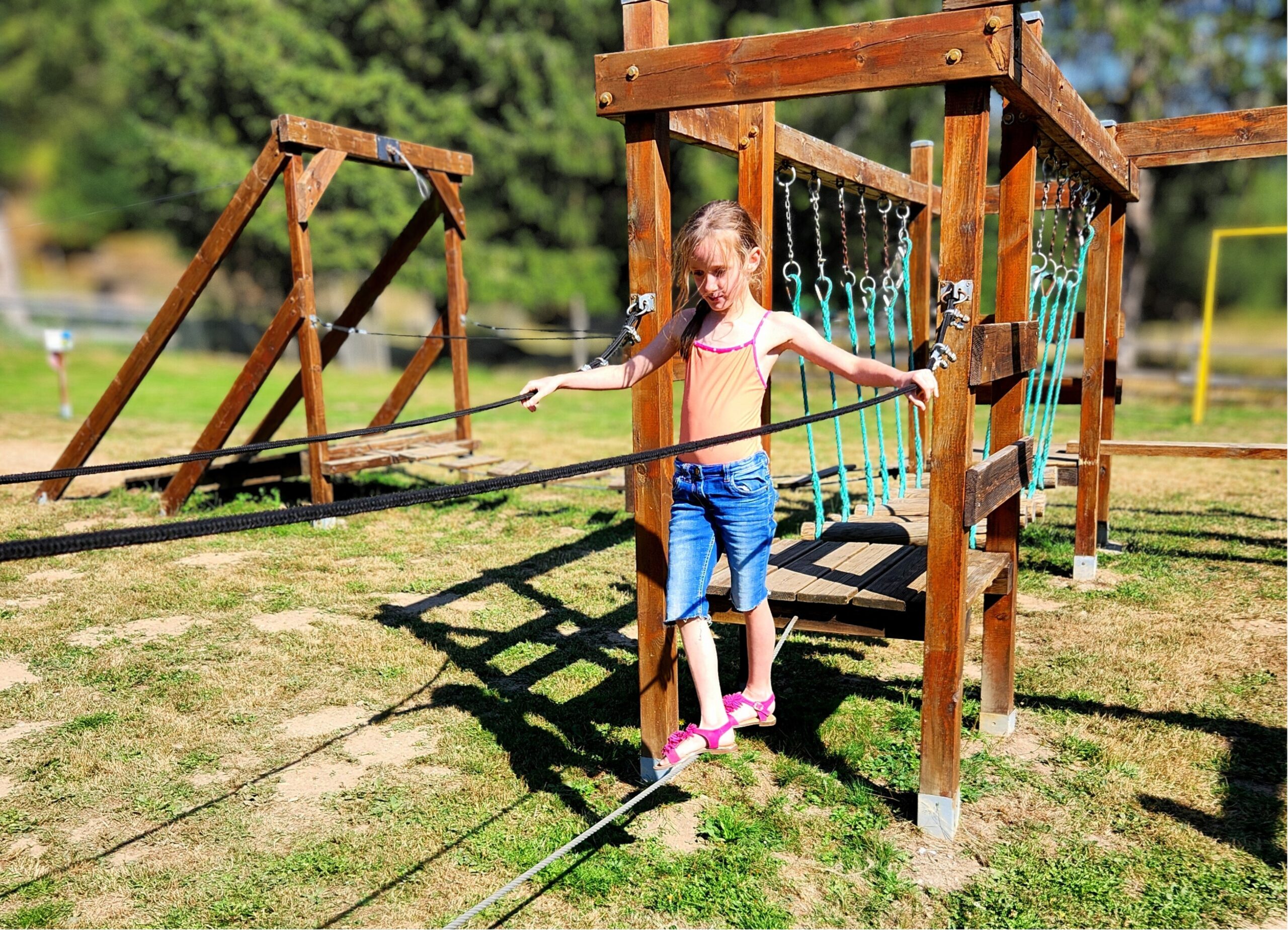 aire de jeux Petite fille jouant sur l’aire de jeux du camping Les Trois Sources, espace ludique et sécurisé pour les enfants.